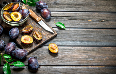 Pieces of fresh plum in a bowl on a cutting Board with a knife.