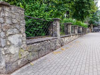 prefab metal fence on concrete foundation pile of stones loose stone construction of houses and yards construction works