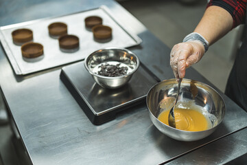 chef pouring caramel in a bowl, circle shapes on a tray in the background, bakery. High quality photo