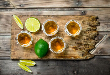 Tequila in a shot glass on a cutting Board with lime.