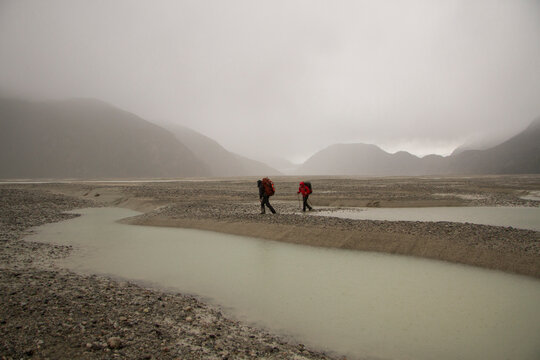 A pair of backpackers trudge along the wet, rough track of the Aysen Glacier region of Patagonia, Chile.