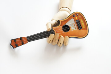 Una chitarra giocattolo tra le dita di una mano artificiale in legno
