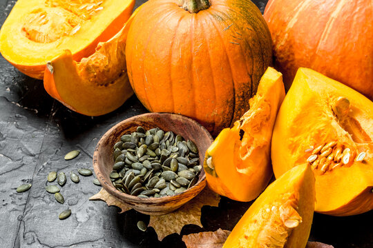 Pumpkin seeds in a bowl and pieces of ripe pumpkin.
