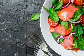 Fish salad. Salad with slices of salmon, tomatoes and spinach with lime juice.