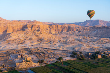 Fototapeta na wymiar Colorful hot air balloon at sunrise in front of Temple of Hatshepsut and Ramesseum near the Valley of the Kings in Luxor, Egypt