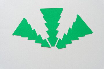 three green paper shapes with zig zag edges on blank paper