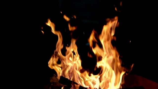 Close-up, flames from fire. Night bonfire, logs are on fire, sparks fly. 4k Super slow motion of flames.