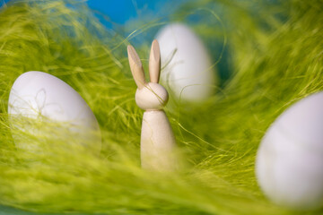 petit lapin en bois silhouette dans de la paille verte avec des oeufs de paques