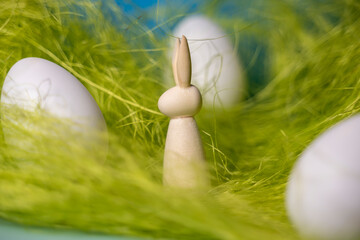 petit lapin en bois silhouette de profil dans de la paille verte avec des oeufs de Pâques
