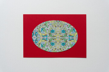 paper oval with fancy decorative pattern on red card and white space