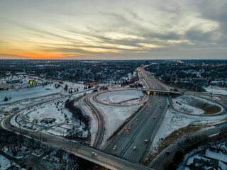 Aerial shot of a snowy cityscape with freeway highway road passing through an urban area at sunset in Omaha Nebraska