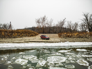 Aerial shot of an Offroad Vehicle near the shoreline of a frozen river