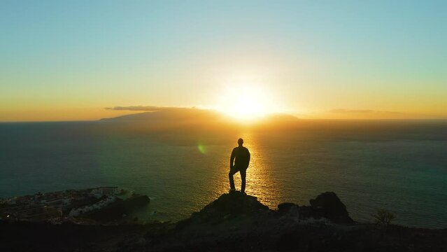 Man looking at sunset on mountain top with ocean view and harbour cityscape on the background. Hiking active healthy lifestyle concept. Natural landscape.