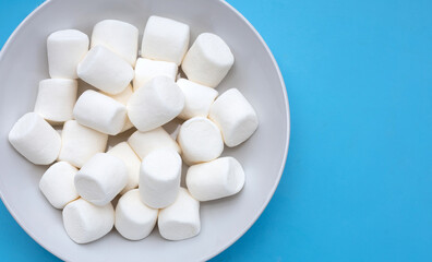 Fototapeta na wymiar Delicious white marshmallows on blue background.