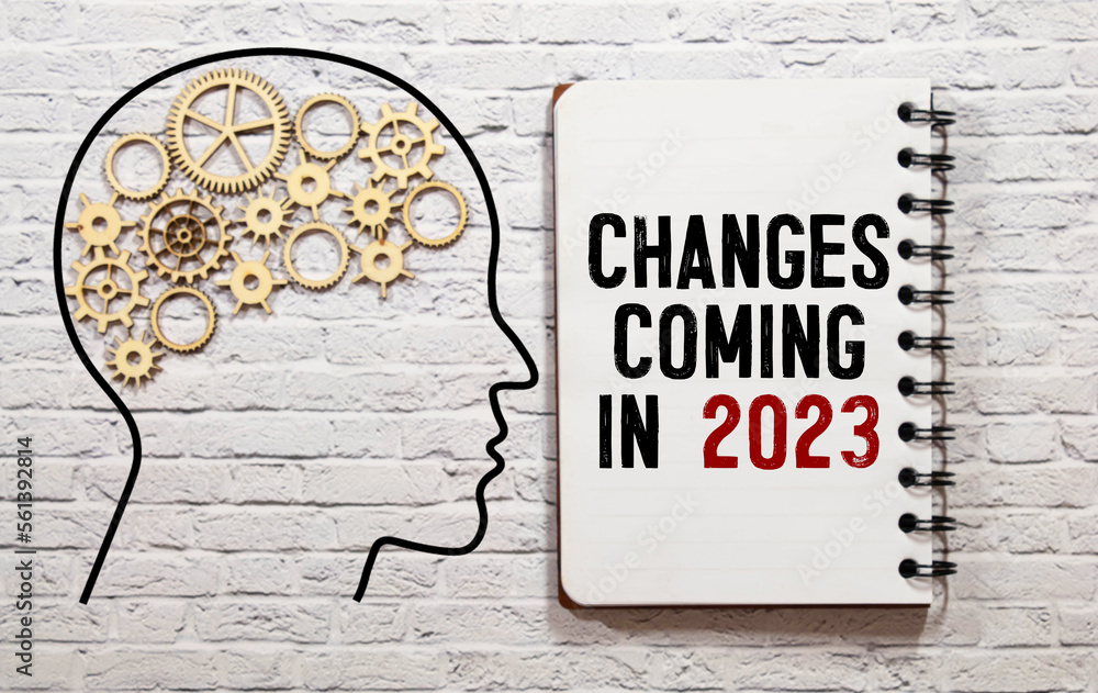 Poster notebook with the word change is coming in 2023 on wooden background