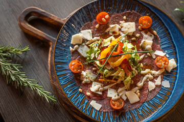 carpaccio Italian style with parmesan cheese flakes on wooden board and cherry tomatoes