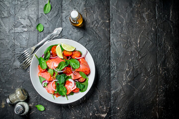 Fish salad. Salad with slices of salmon, tomatoes and spinach with lime juice.