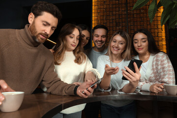 Friends with drinks and smartphones spending time together in cafe