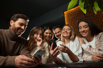 Friends with drinks and smartphones spending time together in cafe, low angle view