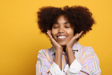 Obraz na płótnie Canvas Portrait of smiling African American woman on orange background