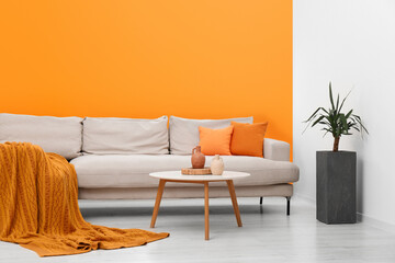 Stylish sofa and coffee table in room with orange walls. Interior design