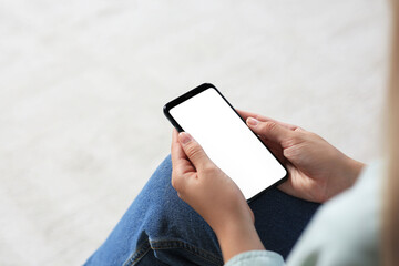 Closeup view of woman with smartphone indoors. Space for text