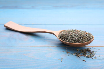 Spoon with dried thyme on light blue wooden table