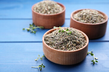 Bowls with dried and fresh thyme on blue wooden table, closeup