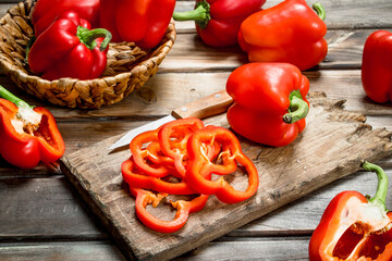 Pieces of fresh pepper on a cutting Board with a knife and a whole sweet pepper in a basket.