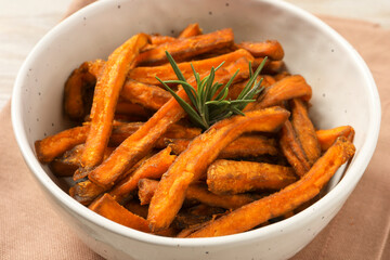 Bowl with sweet potato fries and rosemary on beige cloth, closeup