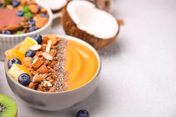 Bowl of delicious fruit smoothie with fresh orange slices, blueberries and granola on white table, closeup. Space for text