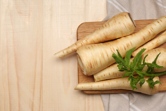 Many fresh ripe parsnips on wooden table, flat lay. Space for text