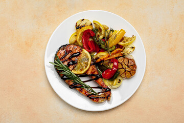 Tasty salmon steak with sauce, lemon and vegetables on light table, top view