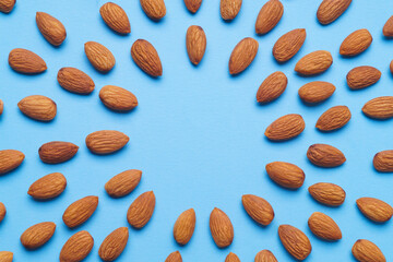 Delicious raw almonds on light blue background, flat lay. Space for text