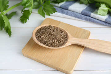 Spoon of celery seeds on white wooden table
