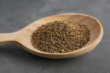 Spoon of celery seeds on grey table, closeup