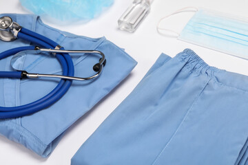 Medical uniform, face mask, stethoscope and antiseptic on white background, closeup view