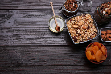 Tasty granola served with nuts and dry fruits on wooden table, flat lay. Space for text