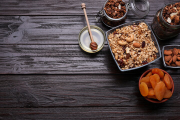 Fototapeta premium Tasty granola served with nuts and dry fruits on wooden table, flat lay. Space for text