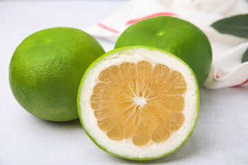 Whole and cut sweetie fruits on white table, closeup