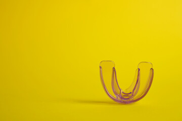 Fototapeta premium Transparent dental mouth guard on yellow background, space for text. Bite correction
