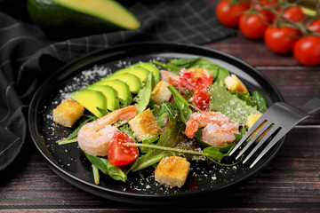 Delicious salad with croutons, avocado and shrimp served on wooden table, closeup