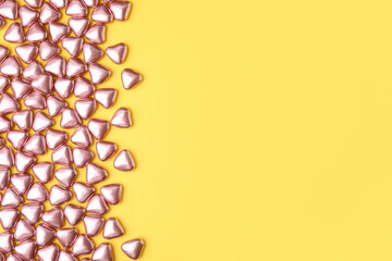 Many delicious heart shaped candies on yellow background, flat lay. Space for text