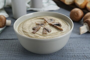 Delicious mushroom cream soup on light grey wooden table, closeup