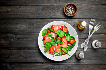 Fish salad. Salad with slices of salmon, tomatoes and spinach with lime juice.