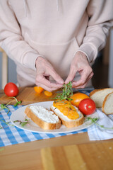 Age woman preparing healthy sandwiches with microgreens and vegetables