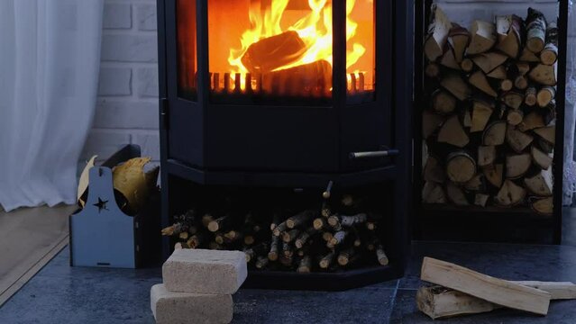 Fuel briquettes made of pressed sawdust for kindling the furnace - economical alternative eco-friendly fuel for the fireplace in the house. Firewood is burning in the oven in the interior