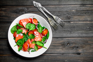 Fish salad. Salad with slices of salmon, tomatoes and spinach with lime juice.