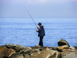 a man is fishing on the breakwater rock