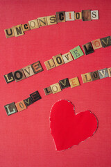 unconscious love (repeated several times) and paper heart with torn edges on red scrapbook paper with texture